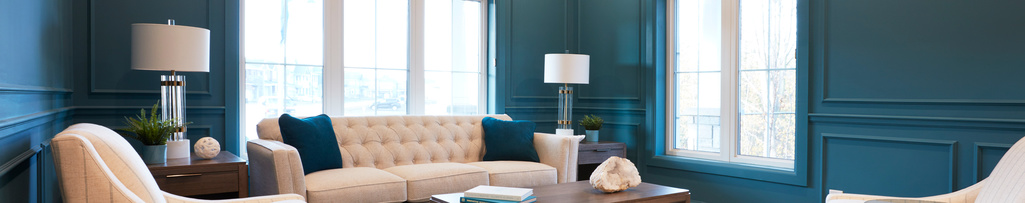 A teal living room with casings around the windows and panel moulding around the walls.
