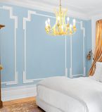 Bedroom with blue walls with white moulding, baseboards and casing