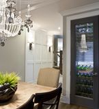 Light grey dining room with white casing on the ceiling and around the wine fridge with dark grey doors