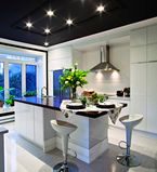 Large white kitchen with white moulding on the wall and a black ceiling that has moulding around the lighting on the ceiling